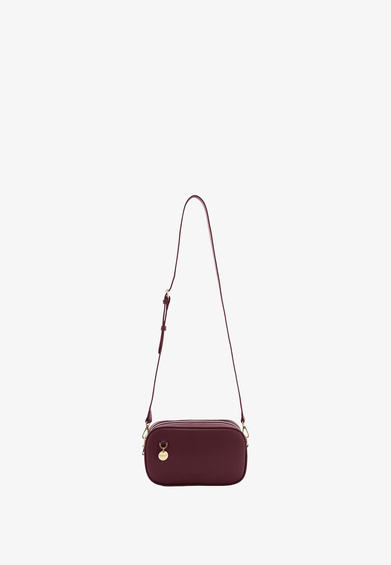 Maroon leather crossbody bag with gold hardware, rectangular shape, adjustable strap, and a small circular charm on the front.