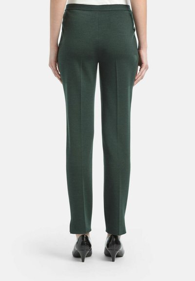 Prilagođene zelene hlače od glatkog materijala, s uskim krojem, ravnim nogavicama i suptilnim bočnim šavovima, uparene s crnim potpeticama.