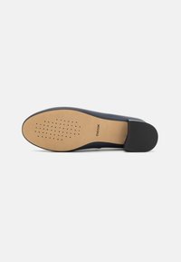 Scarpa marina con tomaia liscia, punta arrotondata e suola perforata color tan traspirante. Tallone nero testurizzato per una presa e stabilità migliori.
