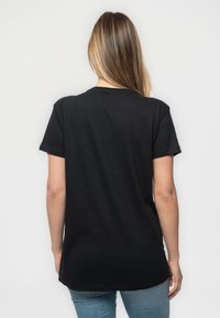 Black cotton t-shirt with short sleeves, round neckline, and a relaxed fit. Back view shows smooth texture and no visible patterns or hardware.