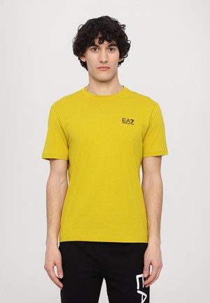 T-shirt in cotone giallo con scollatura tonda e maniche corte. Piccolo logo nero "EA7" nella zona sinistra del petto.