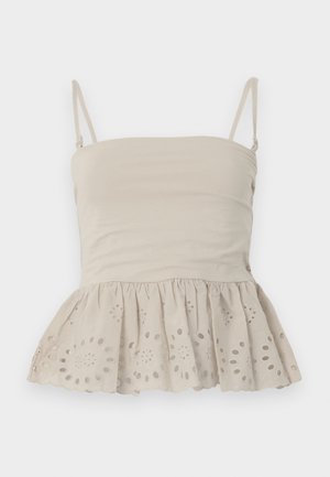 Top sin mangas beige con tirantes finos y dobladillo con volantes con patrones florales recortados en forma circular.