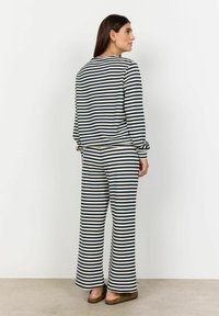 Two-piece outfit featuring a long-sleeve top and wide-leg pants in navy and cream horizontal stripes. Material appears soft and comfortable.