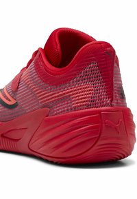 Rød atletiksko med en tekstureret mesh-overdel, polstret krave og gummisål med udtalte riller. Puma-logo på hælen.