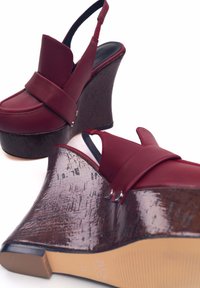 Scarpe con la piattaforma rossa e tacco a zeppa di cuoio marrone texture. Parte superiore in pelle liscia con una larga fascia e cinturino regolabile sul dietro. Suola in gomma.