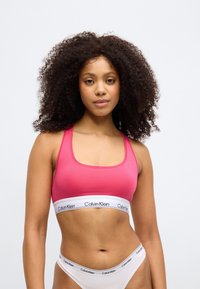Ροζ βαμβακερό μπραλέτ με τετράγωνη λαιμόκοψη και λεπτές τιράντες. Διαθέτει λευκή ελαστική ζώνη με το λογότυπο "Calvin Klein". Απλός, κομψός σχεδιασμός.