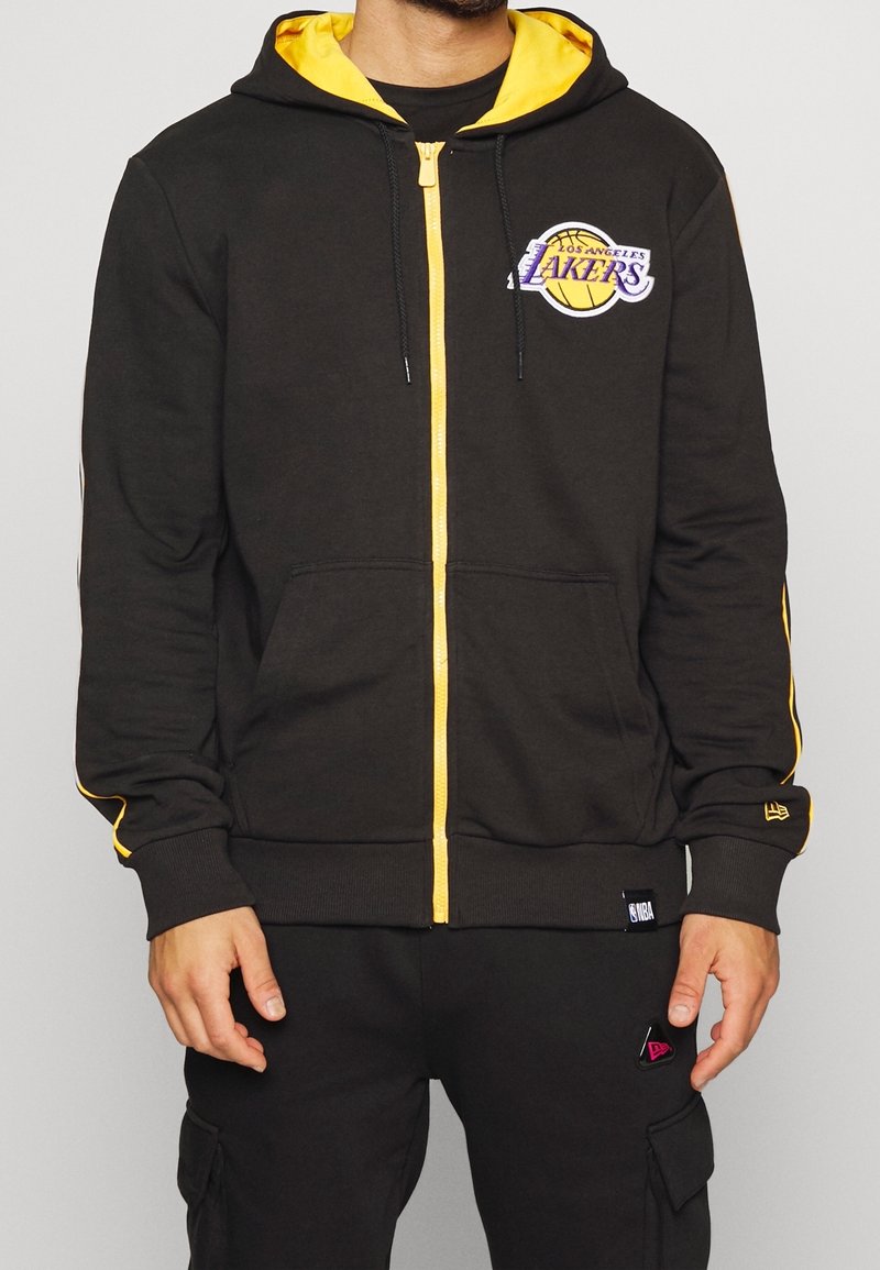 Svart zip-up hoodie med gula detaljer och Los Angeles Lakers-logotyp. Har en huva, kängurufickor och ribbade muddkanter. Tillverkad i bomull.