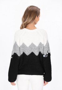 Zigzag mintázatú, vastag kötésű pulóver fehér, szürke és fekete színekben. Fémes díszítésekkel a hosszán és kényelmes, lazán illeszkedő fazon.