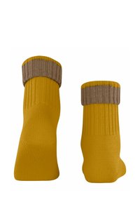 Chaussettes jaunes tricotées avec une texture côtelée et un revers marron replié. Les chaussettes ont une finition lisse et une forme légèrement contourée.