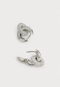 Pendientes en tono plateado con formas metálicas entrelazadas, que presentan un grupo de strass claros y un acabado pulido.