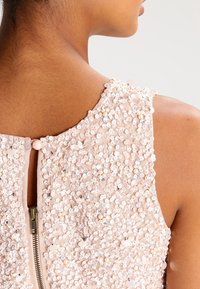 Pailletten-Oberteil mit strukturiertem Stoff. Mit verstreuten Pailletten und Perlen, Rundhalsausschnitt und einem Reißverschluss auf der Mitte hinten mit einem Knopfverschluss.