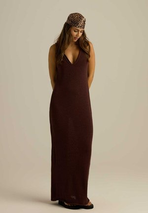 Bordowa dzianinowa sukienka maxi z głębokim dekoltem w kształcie V i bocznymi rozcięciami, w zestawieniu z chustą w leopardzi wzór i czarnymi płaskimi sandałami.