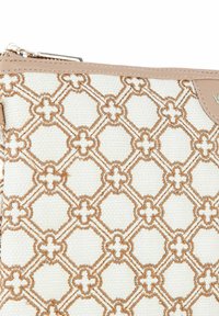 Beige en witte stoffen zak met een verhoogd geometrisch patroon en bloemaccenten, ritsluiting en een gladde beige rand.