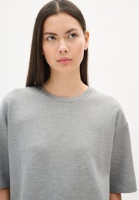 Grijze t-shirt met korte mouwen en een ronde hals. Zachte stof met een gladde textuur, met een ietwat verlaagde schoudernaad voor een ontspannen pasvorm.
