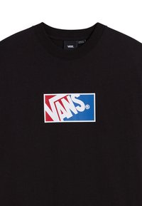 Camiseta de algodón negra con un logo central de Vans en rojo y azul. El cuello es de estilo redondo y la tela parece suave con una textura lisa.