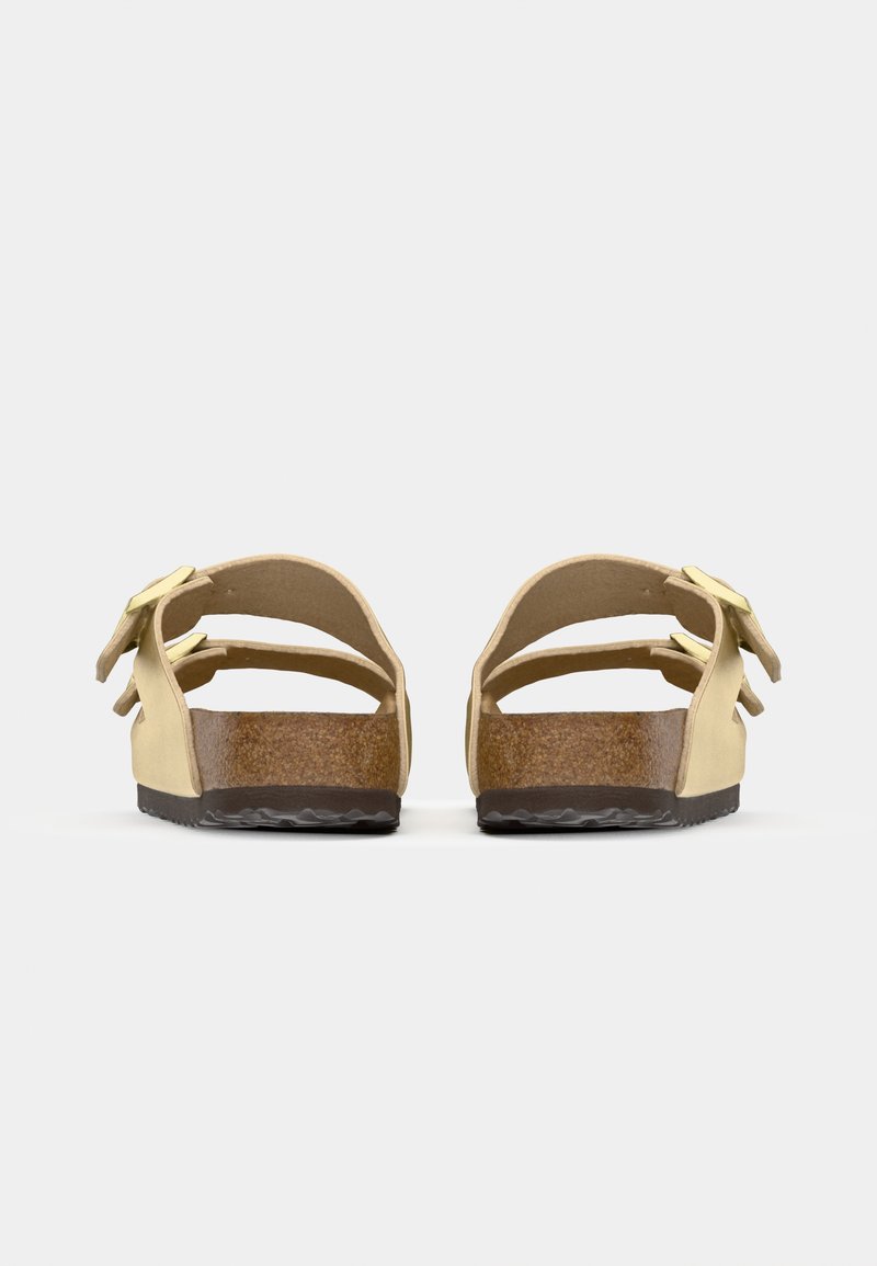 Gelbe Sandalen mit zwei verstellbaren Riemen. Korkfußbett und Gummisohle. Minimalistisches Design mit offenem Rücken und glatter Textur.