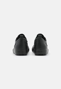 Schwarze Sneakers mit einer glatten, matten Oberfläche. Sie haben ein niedriges Profil, eine Fersenlasche und eine strukturierte Sohle für besseren Grip. Minimalistisches Design ohne Akzente.