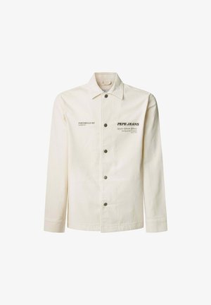 Kreemikas värviga jakk, millel on pikad varrukad, nööbiga kinnitamine ja allaklapitav krae. Omab trükitud teksti ja sileda puuvillase tekstuuri.