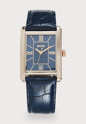 Rectangular gold watch with blue face, Roman numerals, "BOSS" logo, date window at 6 o'clock, and dark blue textured leather strap.