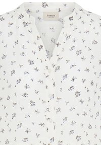 Blouse blanche boutonnée avec un petit imprimé floral marron et bleu clair, et un col rond avec une légère découpe en V.