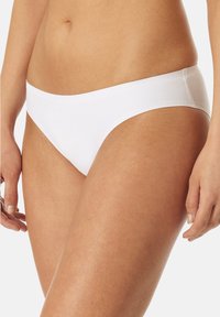 Bikini slip bianco realizzato in un tessuto leggero e morbido con una leggera lucentezza, taglio a vita bassa e design minimalista senza dettagli decorativi.