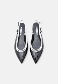 Μαύρα παπούτσια slingback από πατενταρισμένο δέρμα με μυτερή μύτη, λευκή αντίθετη φάσα και ρυθμιζόμενο λουράκι στον αστράγαλο με λεπτομέρειες λογότυπου.