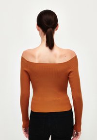 Top off-the-shoulder de canalé en naranja quemado, con mangas largas y una silueta ajustada. Tejido texturizado con un acabado suave.