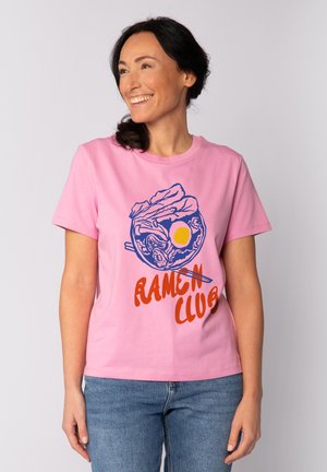 Roze katoenen t-shirt met een blauwe graphic van een ramenkom en oranje tekst met de woorden "RAMEN CLUB." Korte mouwen en een ronde hals.