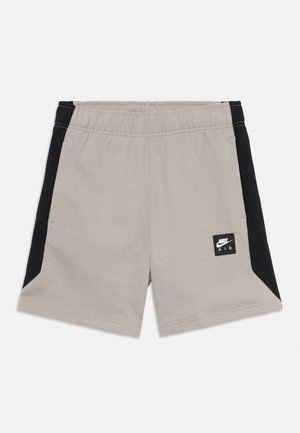 Beige shorts med sorte sidepaneler, elastisk talje og Nike Air logo-patch på venstre bens forside.