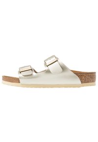 Metallisk gul slidesandal med två justerbara remmar, korkfotbädd och lätt gummisula; slät utseende med en platt design.
