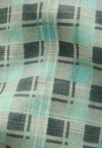 Rutigt tyg med mjukt och lätt material; färger inkluderar ljusgrå, svart och turkos; texturerad väv med horisontella och vertikala linjer.