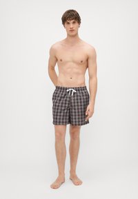 Ανδρικά μαγιό με σκούρο καρό σχέδιο που περιλαμβάνει αποχρώσεις του καφέ, κόκκινου και μπλε. Ελαστική μέση με κορδόνι, μήκος έως το γόνατο, ελαφρύ ύφασμα.