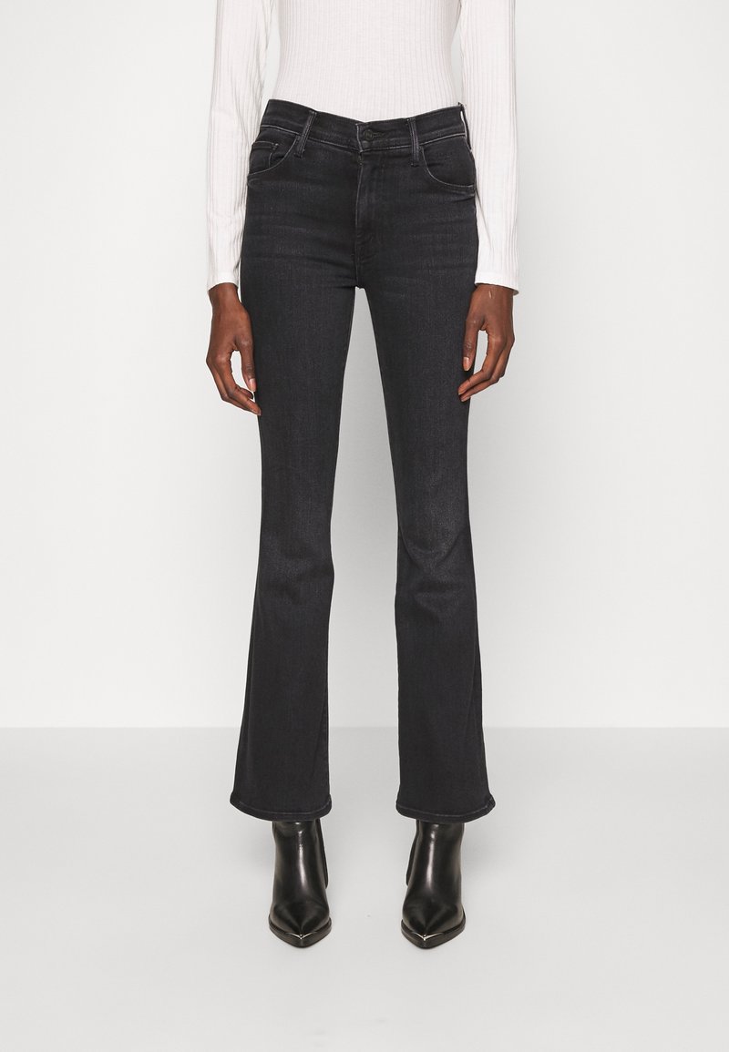 Jeans évasés noirs avec une finition légèrement délavée, taille haute, cinq poches, coupe slim au niveau des cuisses, assortis à des bottes noires pointues.
