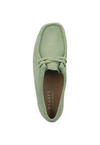 Scarpa in suede verde con punta rotonda, dettagli cuciti e chiusura con lacci. L'interno presenta una fodera beige, con logo impresso sulla soletta.