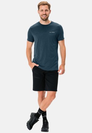 Marineblå t-skjorte med rund hals og korte ermer, kombinert med svarte shorts. Kjennetegn inkluderer enkel logo detalj og teksturert stoff. Svarte sko og mønstrede sokker.