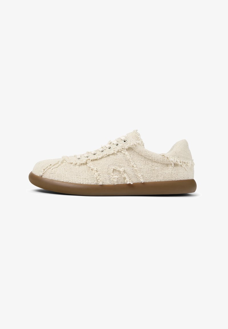 Beige textilsko sneakers med en strukturerad ovandel och fransiga kanter. Har en ljusbrun gummisula och silverfärgade öglor för snörning.