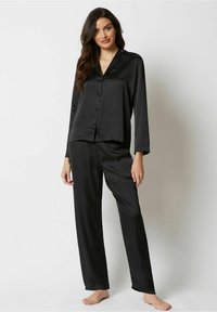 Zwart satijnen pyjama set met een lange mouw button-down shirt en bijpassende rechte broek. Gladde textuur, geen zichtbare patronen of accenten.