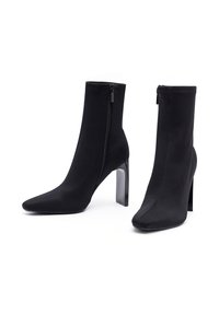 Botines negros de tobillo hechos de una tela suave, con punta afilada, un alto tacón block transparente y una cremallera lateral para el cierre.