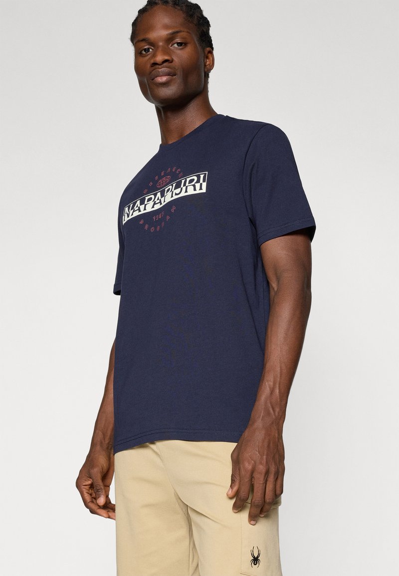 T-shirt en coton bleu marine avec un grand logo imprimé blanc et rouge sur la poitrine. Manches courtes et col rond.