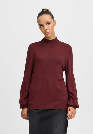 Pull en bourgogne avec un col haut, des manches longues légèrement amples et une texture douce. Design simple sans motifs visibles.