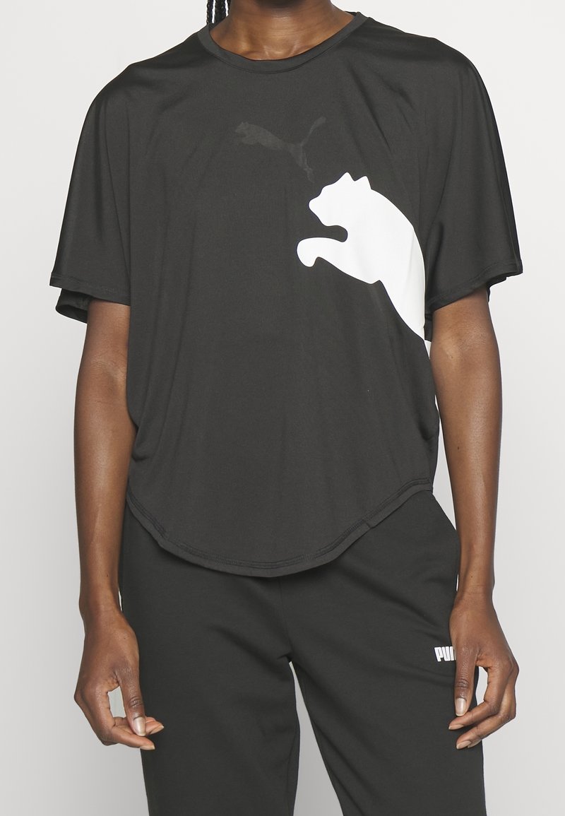 Černé tričko s krátkými rukávy vyrobené z měkké látky, s velkým bílým logem Puma na přední straně. Zaoblený lem a volný střih.