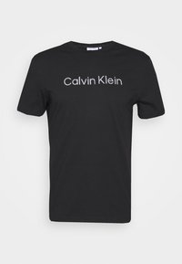 Černé tričko s krátkým rukávem a výstřihem ve tvaru kruhu s bílým logem "Calvin Klein" umístěným na středě přední strany.