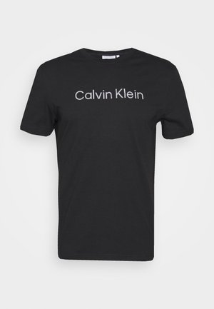 Camiseta negra de manga corta y cuello redondo con el logo blanco de "Calvin Klein" centrado en la parte frontal.