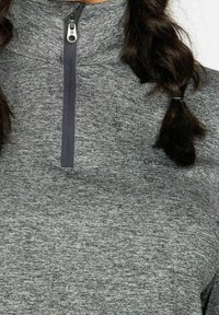 Top grigio con zip e collo alto, dotato di una zip blu navy. Il tessuto ha una finitura testurizzata con un motivo sottile.