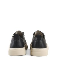 Sneaker in pelle nera con suola in gomma beige, caratterizzate da una superficie liscia, punta rotonda e un gancio posteriore per una facile calzata.