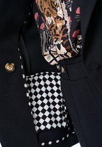 Zwarte blazer met gouden knopen, gevoerd met een gestreepte sjaal en een geruite binnenzak, met stippenaccenten.