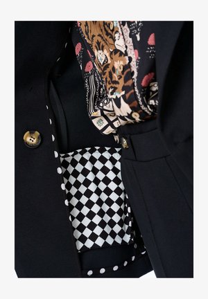 Czarna marynarka z złotymi guzikami, podszewka z wzorzystego szalika i w kieszeni w kratkę, z akcentami w groszki.