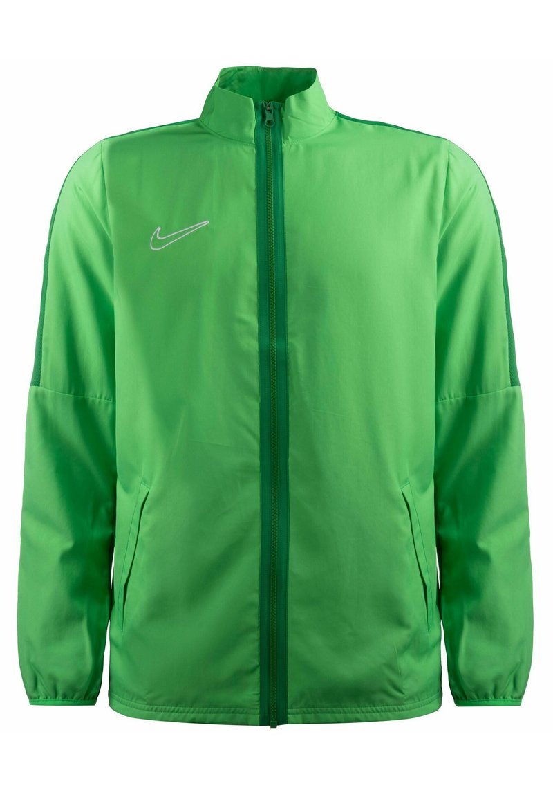 Chaqueta Nike verde ligera con un alto cuello, cremallera frontal, bolsillos laterales y un sutil acento de logo en el lado izquierdo del pecho. Textura de tela suave.