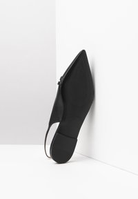 Spidse sorte lædersko med lav hæl, slingback-design, tekstureret sål og præget indvendig branddetaljer.