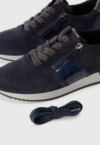 Un paio di sneaker in camoscio blu navy con cerniere laterali, lacci decorati e lacci extra blu navy su uno sfondo bianco.